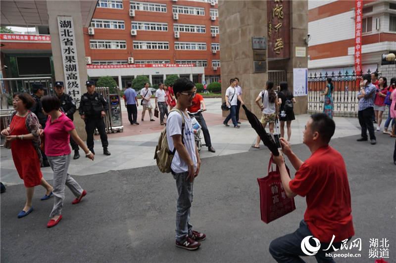 7日下午，在武汉水果湖中学，高考首日结束后，爸爸在考场外给孩子拍照留纪念。（周雯 摄）