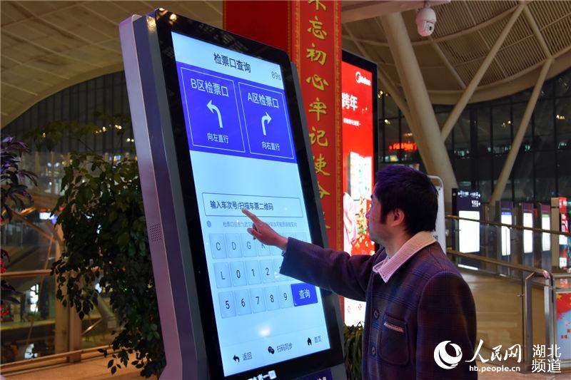 旅客正在使用“畅行九州”APP智能查询机查询检票口信息。(钟明 摄)