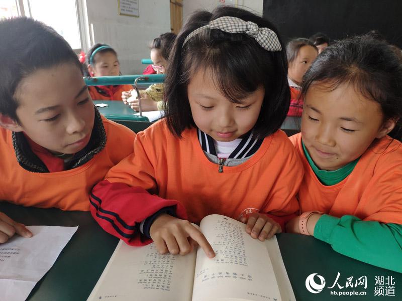 孩子們穿著捐贈的校服正在看捐贈的圖書，臉上流露出幸福的表情   攝影：譚錦濤