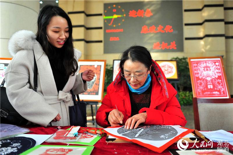 2020年1月17日，湖北省宜昌市夷陵區一名機關干部在觀摩民間藝人黃成翠創作“廉潔剪紙”作品。