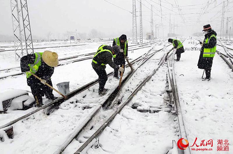 信陽車站組織職工對道岔進行掃雪除冰。（胡婧 攝）