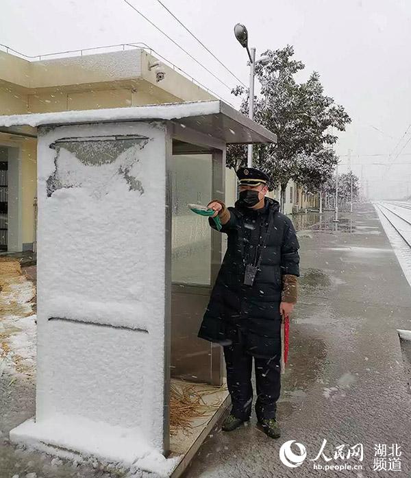 襄陽車站職工袁靜正在風雪中立崗接車。（李濤 攝）