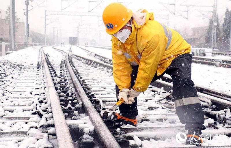 麻城工務段職工正在清掃道岔轉轍部位積雪，確保鐵路安全暢通。（賀勇 攝）