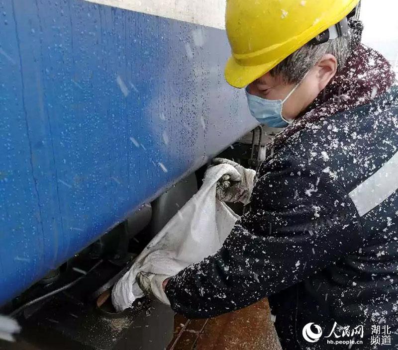 武昌南機務段職工張天喜冒雪給出庫機車上砂。（周凱 攝）