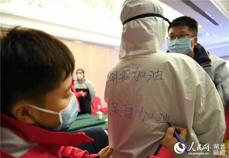 2020年2月17日，一名遼寧省對口支援湖北省襄陽市保康縣人民醫院醫療隊隊員在隊員后背寫上“湖北加油”“保康加油”字樣。