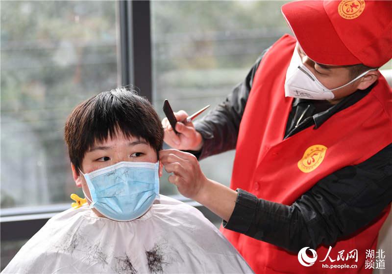 2020年2月17日，一名志願者為遼寧省對口支援湖北省襄陽市保康縣醫療隊隊員秦葉紅理發。