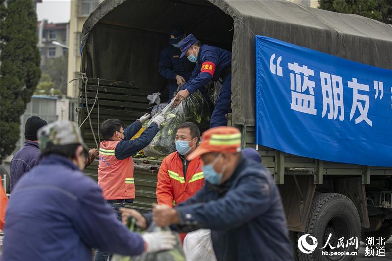 2020年2月26日，湖北省襄陽市消防救援支隊黨員突擊隊消防指戰員將蔬菜送到一線環衛工人手中。（楊東 蘇曉杰 攝）