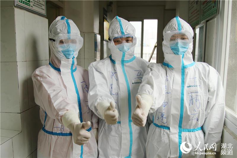 2020年3月8日，在湖北省十堰市鄖陽區人民醫院，廣西援鄖戰“疫”醫療隊隊員唐玲（左）、馬玉（中）、王麗雲（右）在進入隔離病區前為自己點贊加油。（曹忠宏 攝）