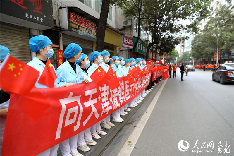 3月24日，鶴峰縣醫院醫護人員與當地居民一起拉起橫幅，歡送天津市支援鶴峰醫療隊返程。