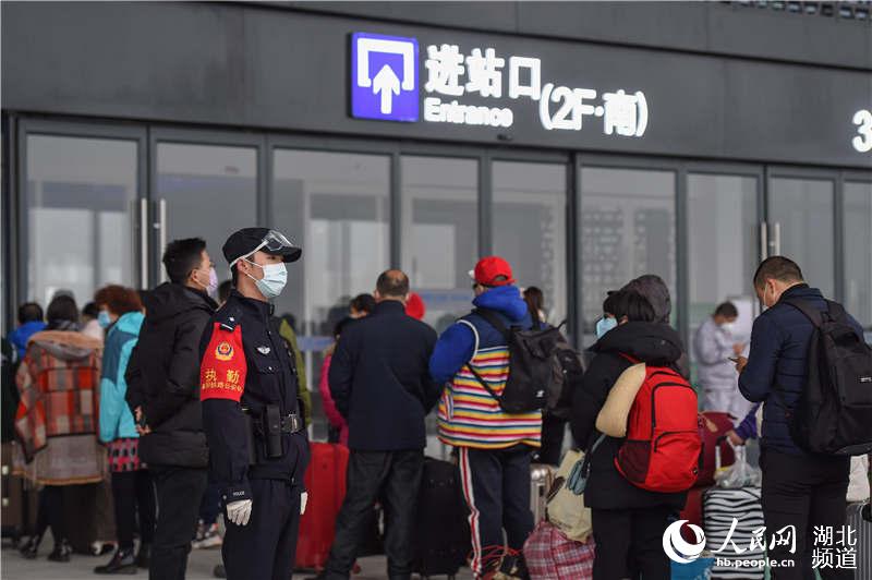 3月28日，乘坐G6860次列車的旅客在襄陽東高鐵站進站口排隊等候進站，武漢鐵路公安局襄陽公安處民警在現場值守。（施勇 攝）
