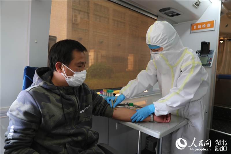武漢科技大學醫院醫務人員在移動體檢車上進行血常規檢查（攝影：張賓）