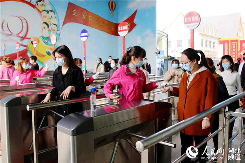 2020年4月5日，在湖北省十堰市鄖陽區子胥湖歡樂嘉年華，工作人員為游人檢測體溫。