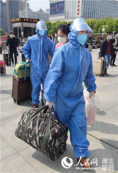 4月8日上午，在漢口火車站站前廣場，旅客們戴囗罩，穿著防護服，保持間距，有序排隊進站候車。