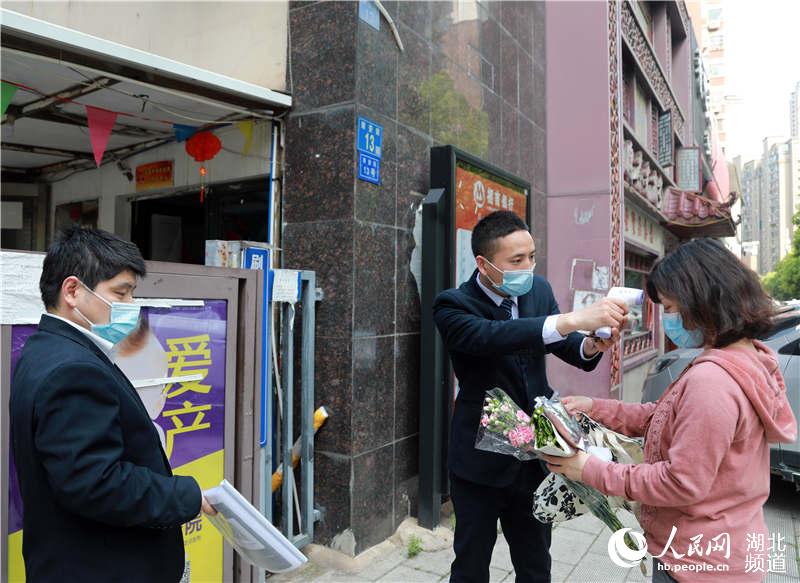 2020年4月13日，在武漢市武昌區站前陽光小區，一物業人員（圖中）正在給入區居民測量體溫。