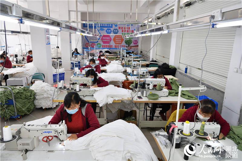 2020年4月24日，在湖北省襄陽市保康縣馬良鎮雞冠河易地扶貧搬遷集鎮集中居民點，工人在服飾加工扶貧車間裡工作。