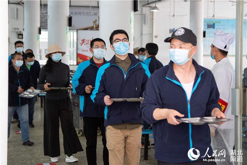 4月25日，在湖北省襄陽市第一中學，參加模擬演練的高三年級老師演練學生在食堂排隊取餐。