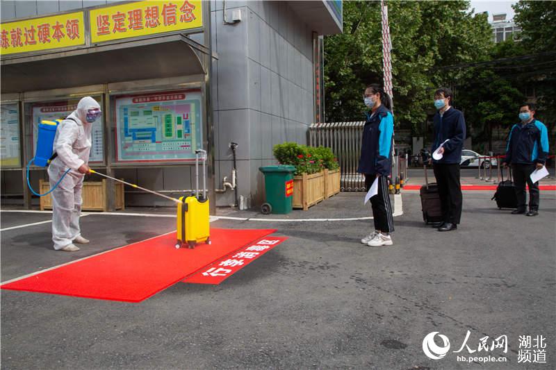 4月25日，在湖北省襄陽市第一中學，工作人員模擬演練給返校學生的行李消毒。