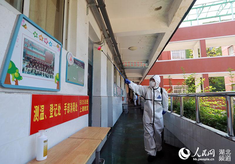 2020年5月19日，在湖北省武漢市糧道街中學，1名消防員正在對上課教室外的走廊區域進行全面消殺