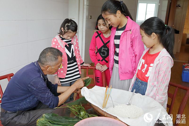 鶴峰縣五裡鄉瓦屋村詹光艷家裡，兒孫們在長輩的指導下學習包粽子。（汪正璽 攝）