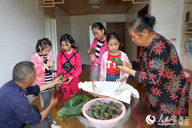 鶴峰縣五裡鄉瓦屋村詹光艷家裡，兒孫們在長輩的指導下學習包粽子。（汪正璽 攝）
