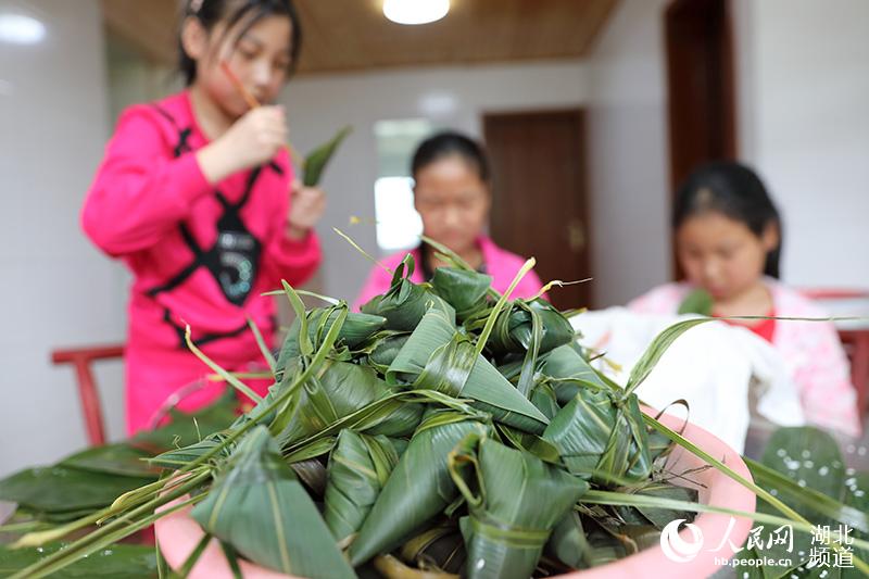 鶴峰縣五裡鄉瓦屋村詹光艷家裡，兒孫們在長輩的指導下學習包粽子。（汪正璽 攝）