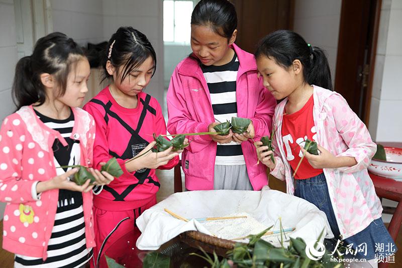 鶴峰縣五裡鄉瓦屋村詹光艷家裡，兒孫們在長輩的指導下學習包粽子。（汪正璽 攝）