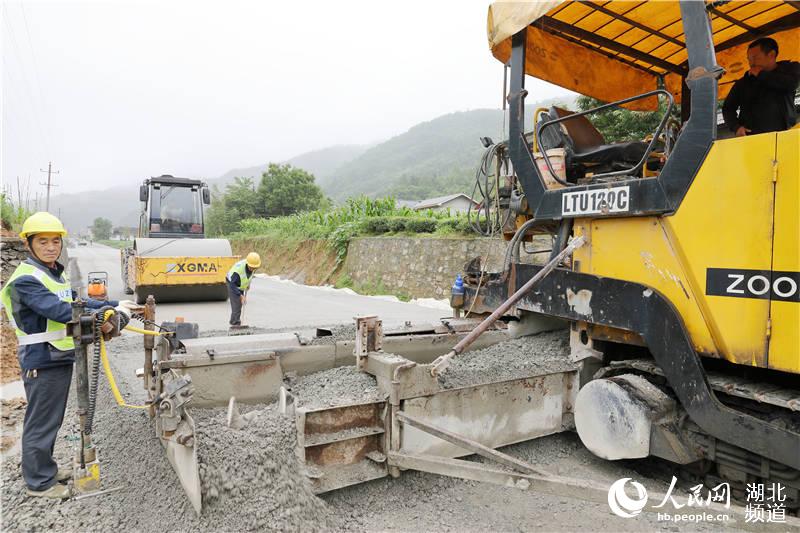 鶴峰縣五裡鄉瓦屋村農村公路改擴建工地上，工人們正冒著風雨、搶抓工期緊張施工。（汪正璽 攝）