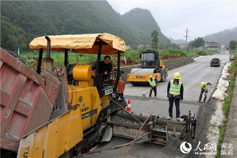 鶴峰縣五裡鄉瓦屋村農村公路改擴建工地上，工人們正冒著風雨、搶抓工期緊張施工。（汪正璽 攝）