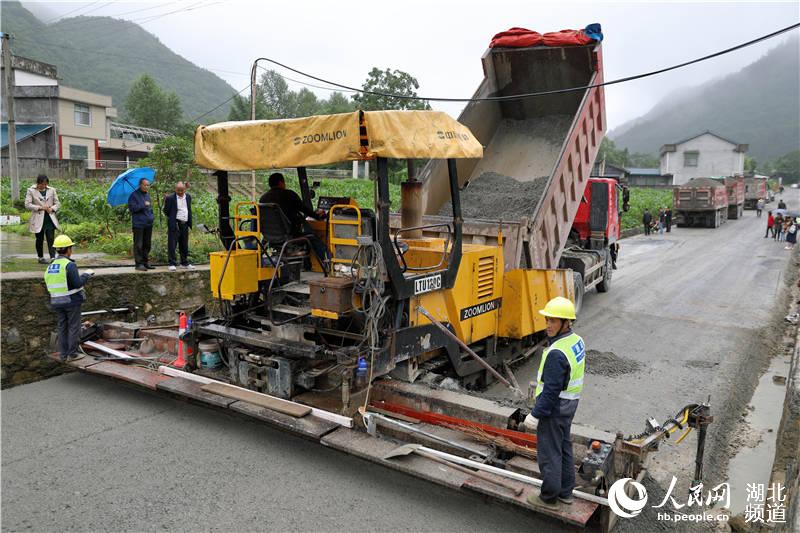 鶴峰縣五裡鄉瓦屋村農村公路改擴建工地上，工人們正冒著風雨、搶抓工期緊張施工。（汪正璽 攝）