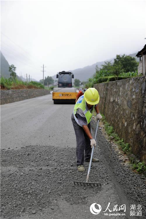 鶴峰縣五裡鄉瓦屋村農村公路改擴建工地上，工人們正冒著風雨、搶抓工期緊張施工。（汪正璽 攝）