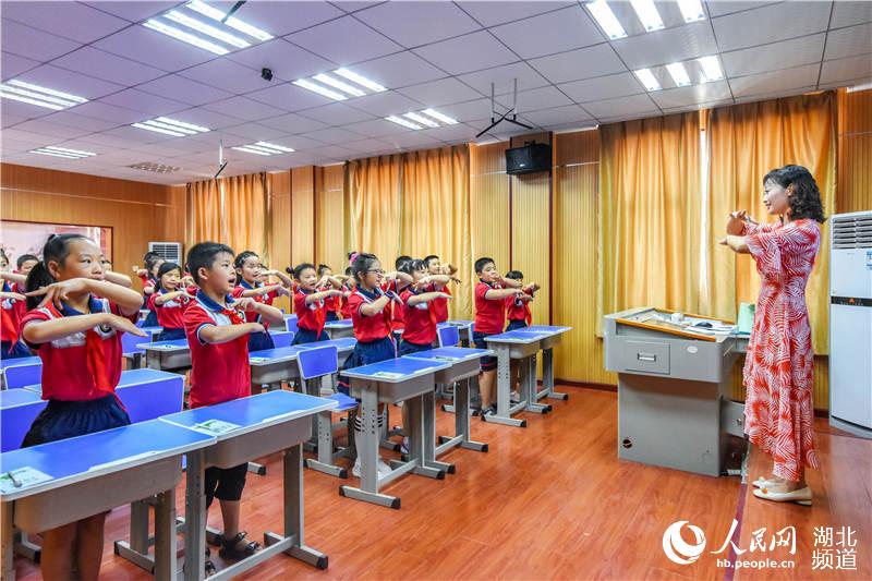 學生跟著老師唱“文明過馬路”兒歌。
