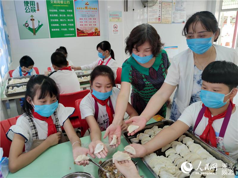 圖為吳善蓮（中）與孩子們一起比包餃子質量。