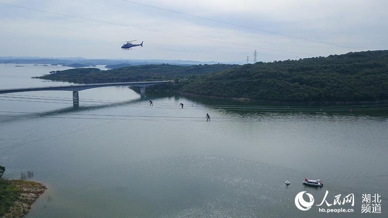 國網湖北檢修公司高空走導線人員與直升機同時對線路進行高空驗收。（夏立偉 攝）