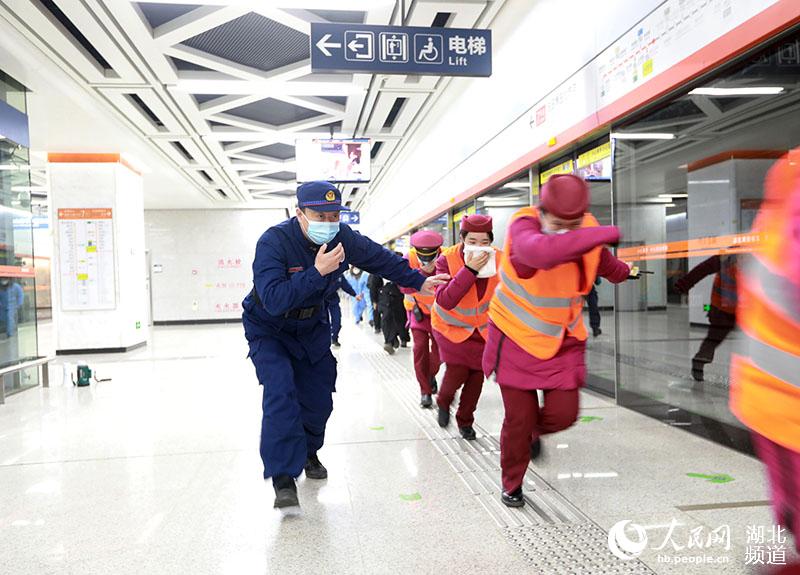 1月28日凌晨，在武漢湖北大學地鐵站內，消防員（圖左）正帶領地鐵工作人員開展應急疏散演練