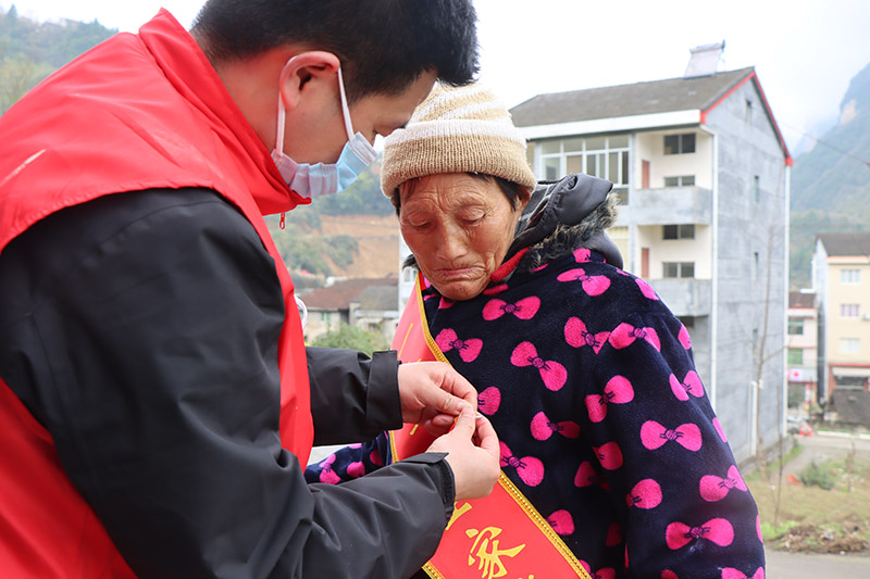 突擊隊志願者為立功軍人家屬佩戴綬帶、大紅花。