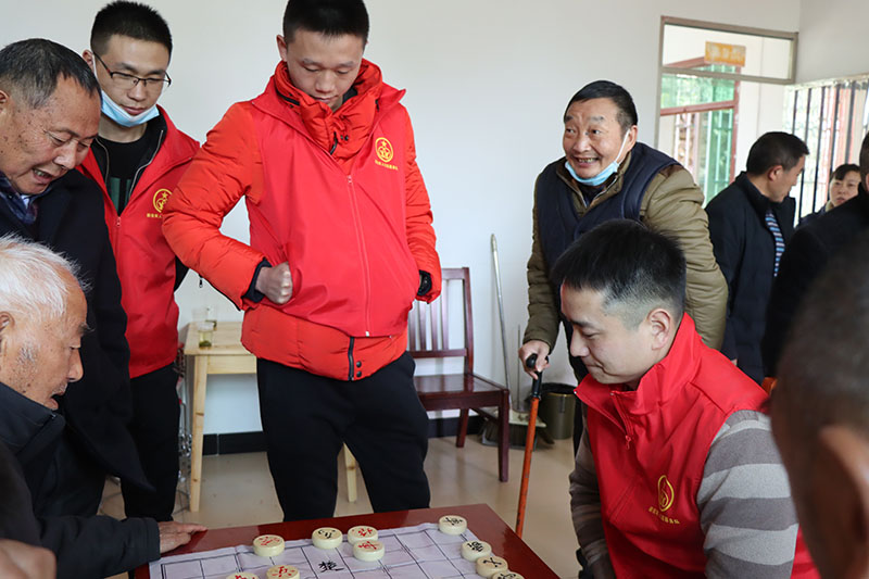 志願服務隊隊員陪福利院老人下象棋。