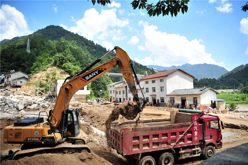 7月25日，大型挖掘機和運輸車在湖北省宜昌市夷陵區樂天溪鎮蓮沱村牛溪口遭受洪澇災害現場對泥石流砂石進行裝運清除。