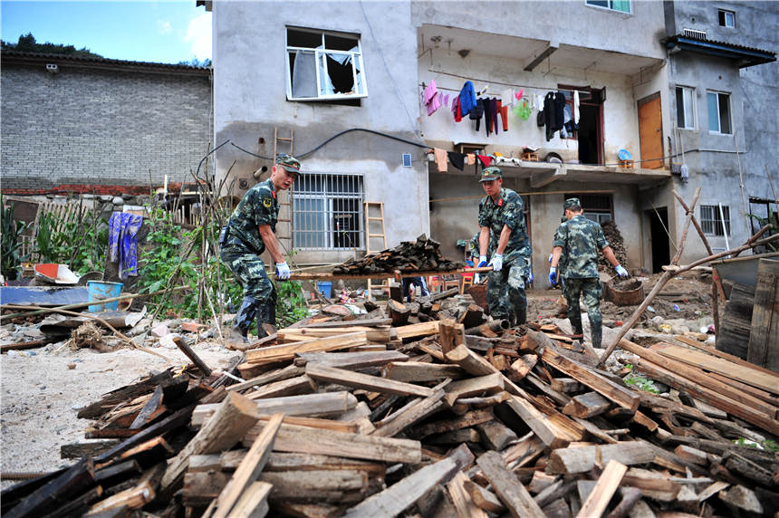 7月25日，武警官兵在湖北省宜昌市夷陵區樂天溪鎮蓮沱村牛溪口遭受洪澇災害現場幫助受災群眾清理轉運木材。