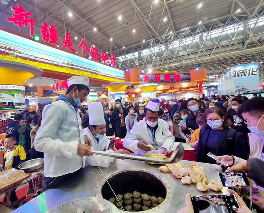 11月27日下午，參展龍頭企業在現場烤制馕、包子、羊肉等新疆特色美食，吸引了湖北武漢市民消費者現場品味、購買。