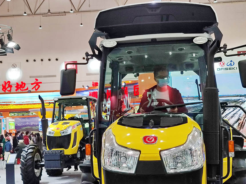 11月27日，在2021湖北農業博覽會上，農機裝備展區展出了一台東風井關EN1004羿農無人駕駛拖拉機，有觀眾在駕駛室試駕。