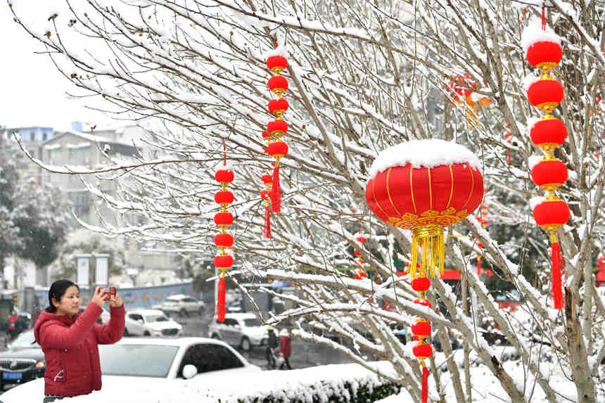 1月28日，游客在湖北省襄陽市保康縣城一處街心花園拍攝雪景。