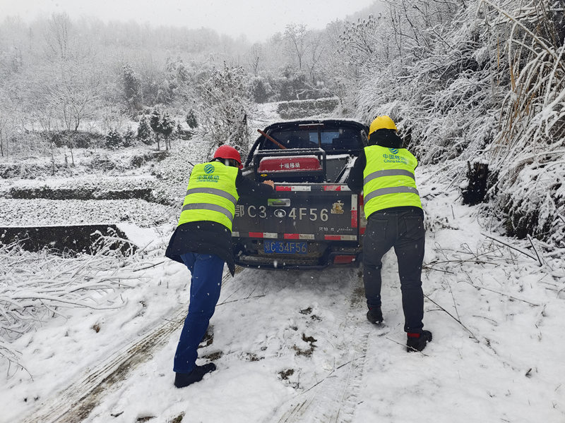 湖北移动抢修人员不畏严寒，在积雪中用力推着抢修车辆赶往故障点