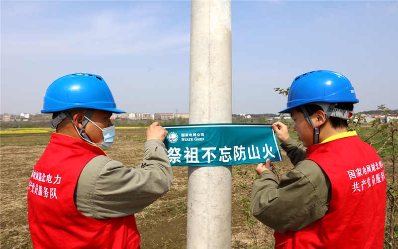 国网广水市供电公司国家电网湖北电力党员服务队在蔡河镇张贴“文明祭祖”小贴士。李紫娅摄