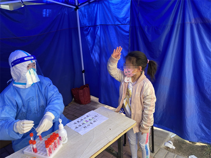 一位8歲女孩做完核酸后向武漢市中心醫院醫療隊醫護人員敬禮致謝。受訪者供圖