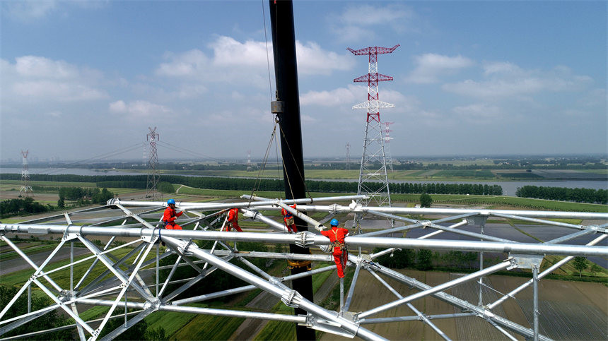 国网湖北电力施工人员在1000千伏荆门至武汉输电线路1049L号铁塔上安装塔材。邹小民摄