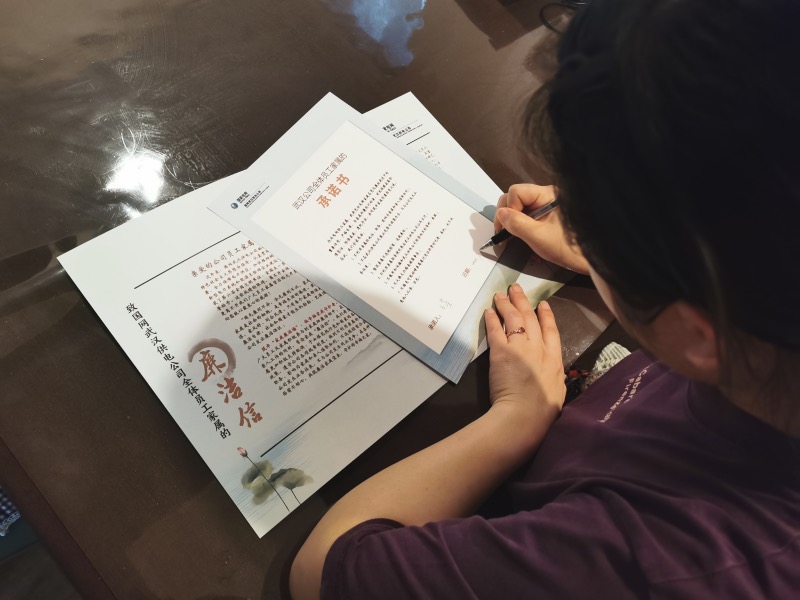 家属正在《武汉公司全体员工家属的承诺书》上签字。