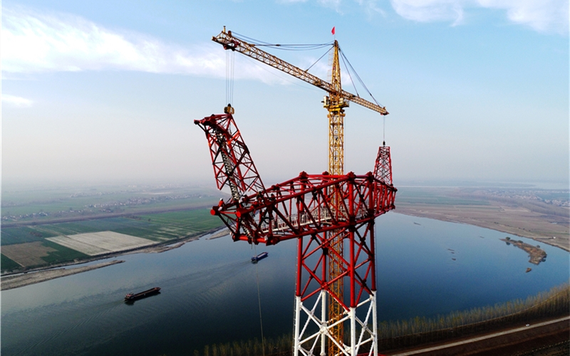 国网湖北送变电公司施工人员采用双平臂抱杆机械化作业吊装高塔。邹小民摄
