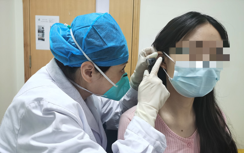 賈敏副主任醫師為患者檢查耳道。