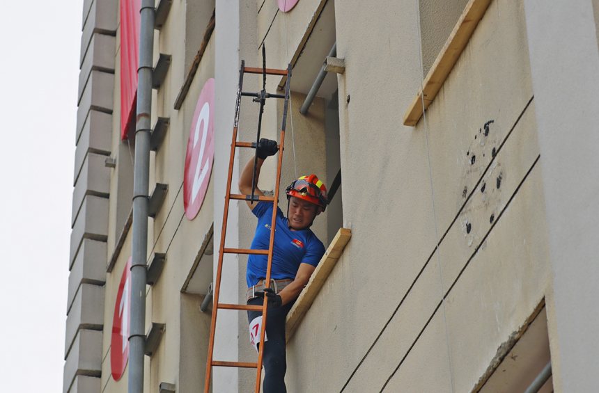 消防指战员正在进行挂钩梯上四楼比赛项目。郭敬仁摄