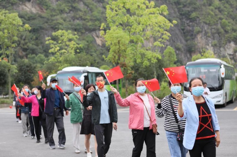游客手持小国旗在景区打卡拍照，国庆气氛满满 。徐军摄